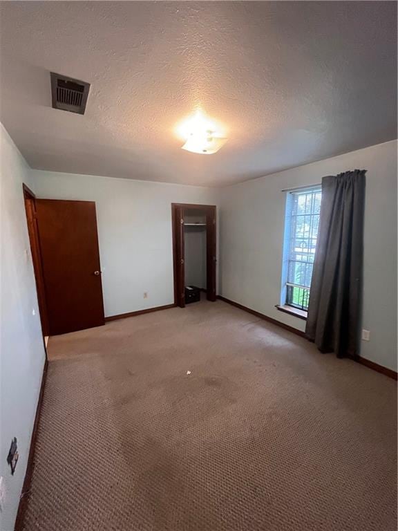 unfurnished room with a textured ceiling and light colored carpet