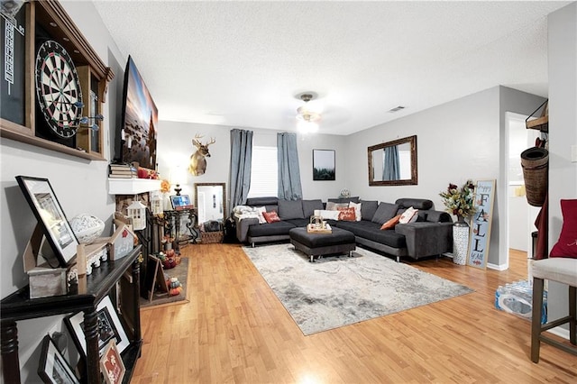 living room with a textured ceiling, hardwood / wood-style flooring, and ceiling fan