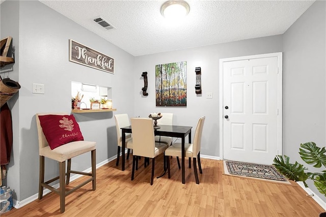 dining area with light hardwood / wood-style flooring and a textured ceiling