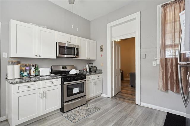 kitchen featuring appliances with stainless steel finishes, light hardwood / wood-style flooring, white cabinetry, and dark stone countertops