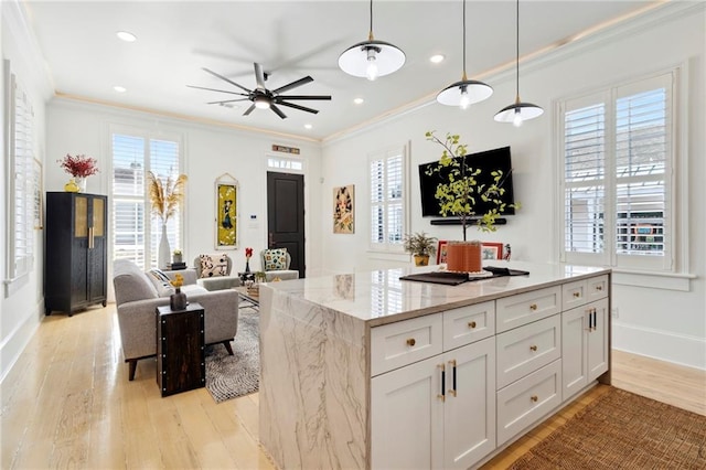 kitchen with white cabinetry, light stone countertops, light hardwood / wood-style flooring, ornamental molding, and decorative light fixtures