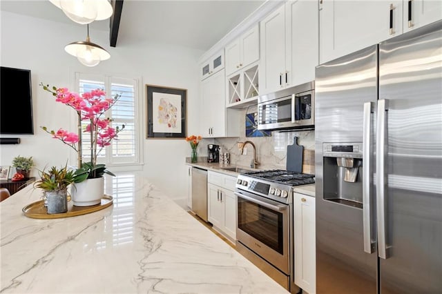 kitchen with light stone countertops, appliances with stainless steel finishes, sink, backsplash, and white cabinets