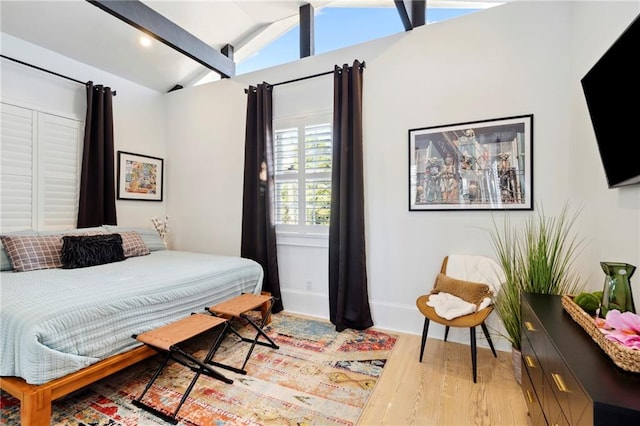 bedroom featuring lofted ceiling with beams and light wood-type flooring