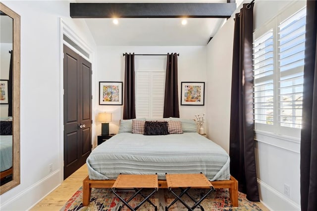 bedroom featuring a closet, multiple windows, beam ceiling, and hardwood / wood-style flooring