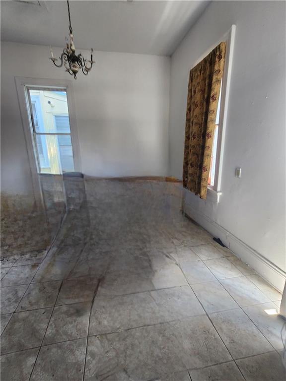 empty room featuring an inviting chandelier and dark tile patterned flooring