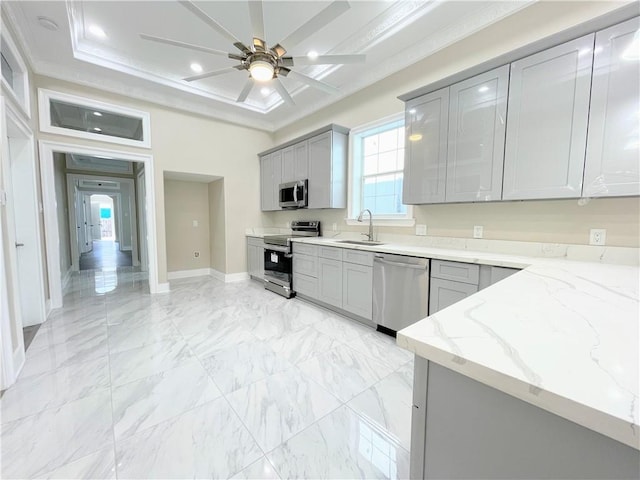 kitchen featuring sink, gray cabinetry, crown molding, light stone countertops, and appliances with stainless steel finishes