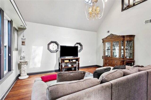 living room featuring high vaulted ceiling, hardwood / wood-style floors, a baseboard heating unit, and an inviting chandelier