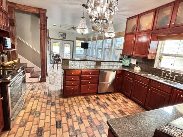 kitchen featuring appliances with stainless steel finishes, a healthy amount of sunlight, decorative backsplash, pendant lighting, and sink