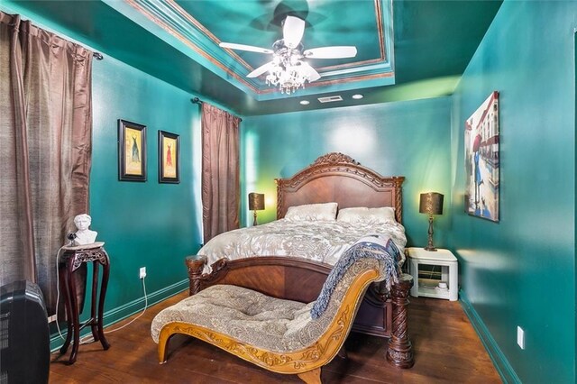 bedroom featuring ceiling fan, ornamental molding, wood-type flooring, and a raised ceiling