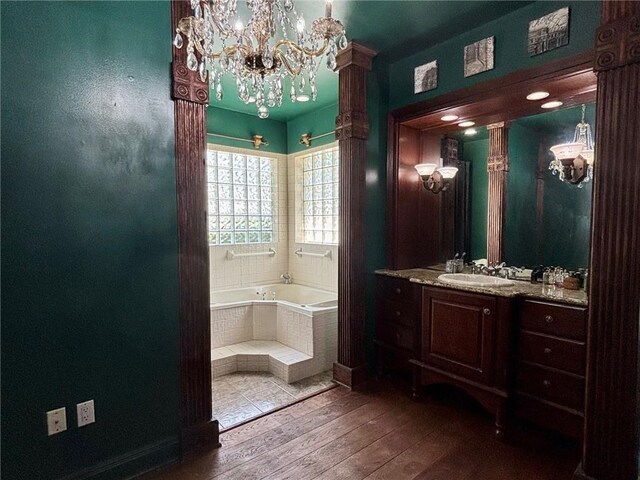 246 Cypress St, Independence, LA 70443 - full bath with vanity, a bath, a notable chandelier, and hardwood / wood-style floors