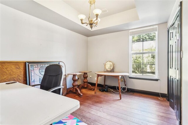 office featuring a wealth of natural light, a tray ceiling, a chandelier, and hardwood / wood-style floors