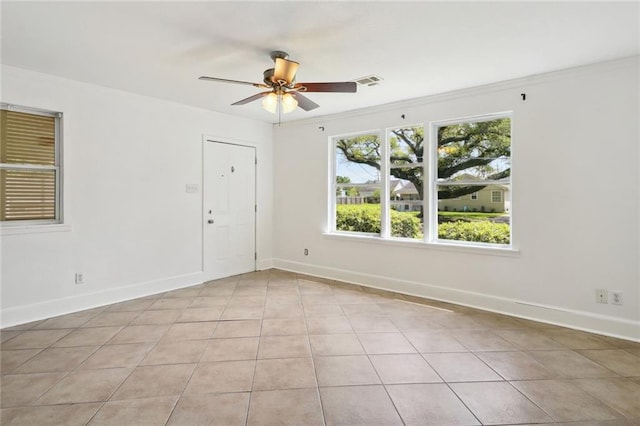 empty room with ornamental molding, light tile patterned flooring, and ceiling fan