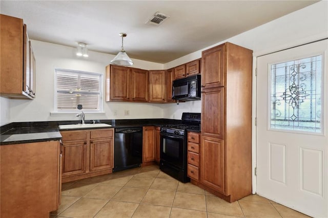 kitchen featuring light tile patterned flooring, black appliances, hanging light fixtures, and sink