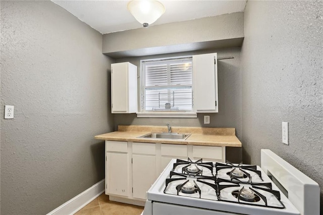 kitchen featuring white cabinetry, sink, light tile patterned floors, and white stove