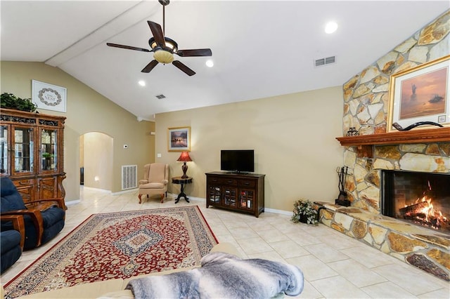 living room featuring a stone fireplace, ceiling fan, light tile patterned floors, and lofted ceiling