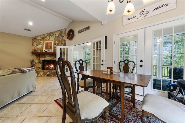 tiled dining room featuring a fireplace, french doors, vaulted ceiling with beams, and a wealth of natural light