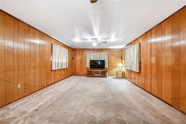 unfurnished living room with light carpet, wooden walls, and ceiling fan