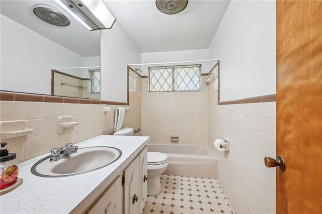 full bathroom with toilet, tile walls, vanity, tiled shower / bath combo, and tile patterned flooring