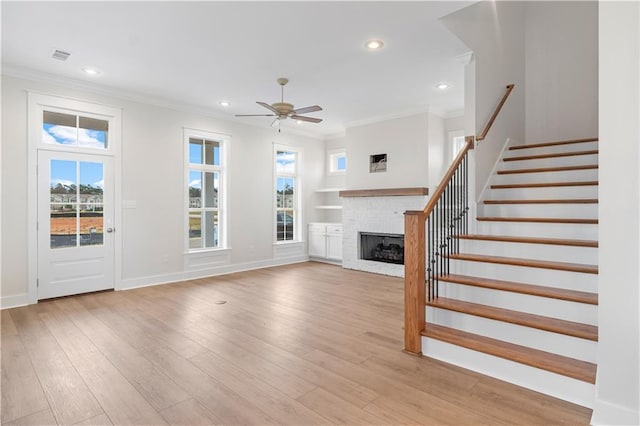 unfurnished living room with light hardwood / wood-style flooring, ceiling fan, a brick fireplace, and crown molding