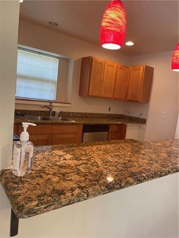 kitchen with dark stone counters, a sink, stainless steel dishwasher, and recessed lighting