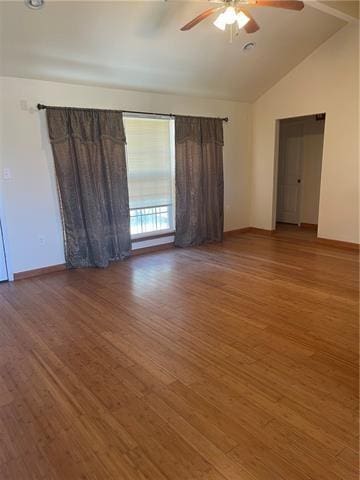 spare room featuring light wood-style flooring, baseboards, vaulted ceiling, and a ceiling fan