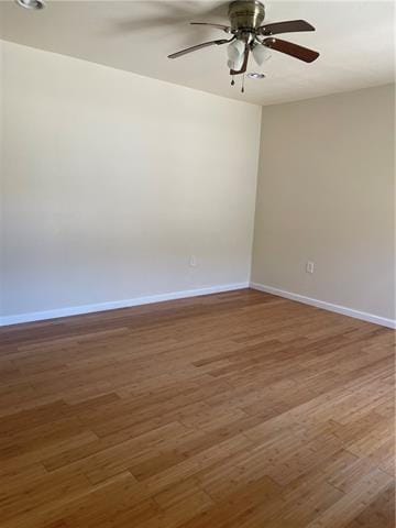 spare room featuring ceiling fan, baseboards, and wood finished floors