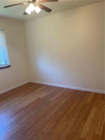 empty room featuring a ceiling fan, baseboards, and wood finished floors