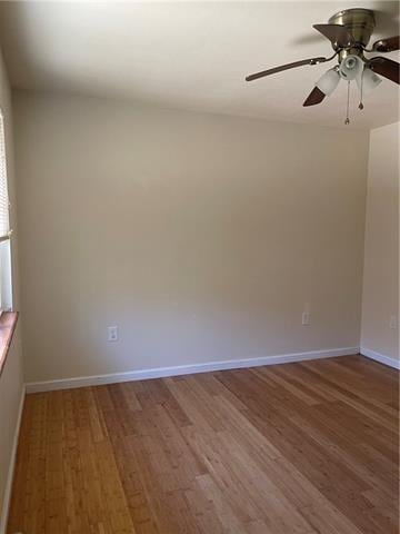 empty room with a ceiling fan, baseboards, and wood finished floors