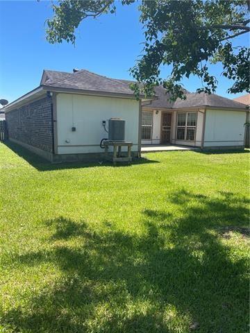 back of property with a yard and central AC unit