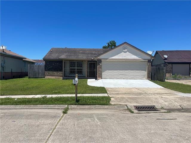 single story home with a garage, concrete driveway, brick siding, and a front yard