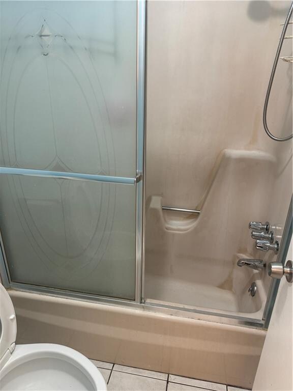 bathroom featuring toilet, tile patterned floors, and shower / bath combination with glass door