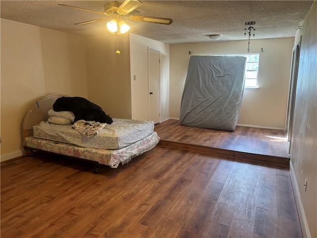 bedroom with a textured ceiling, hardwood / wood-style flooring, and ceiling fan