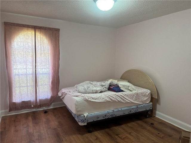 bedroom with a textured ceiling and dark hardwood / wood-style flooring