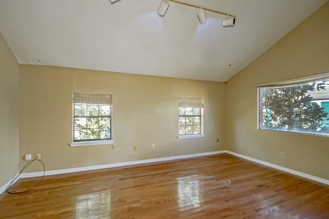 unfurnished room featuring track lighting, vaulted ceiling, and hardwood / wood-style flooring