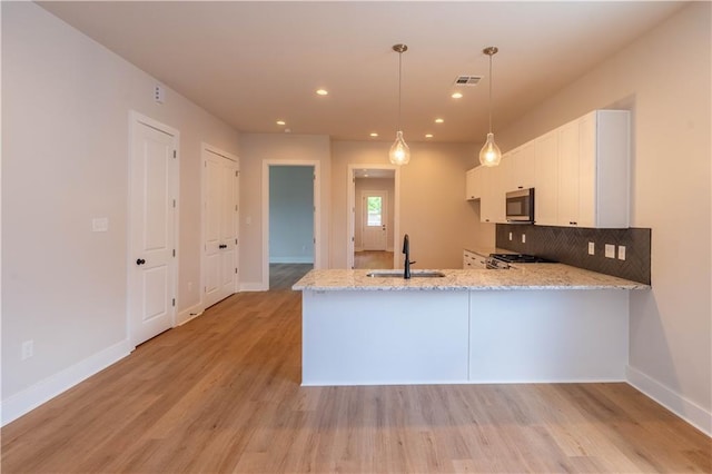 5144 Richland Ave, Marrero, LA 70072 - kitchen with appliances with stainless steel finishes, a sink, a peninsula, white cabinets, and light stone counters