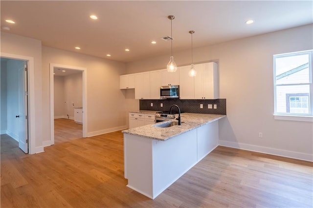 5144 Richland Ave, Marrero, LA 70072 - kitchen with stainless steel appliances, a sink, light stone countertops, a peninsula, and baseboards
