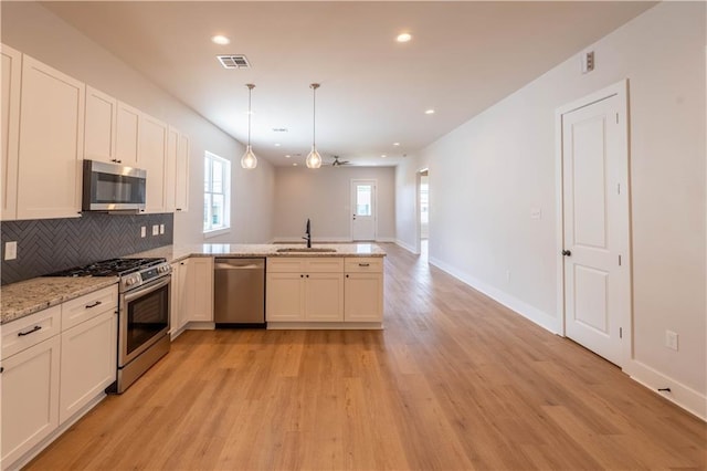 5144 Richland Ave, Marrero, LA 70072 - kitchen featuring stainless steel appliances, a peninsula, light wood finished floors, a sink, and decorative backsplash