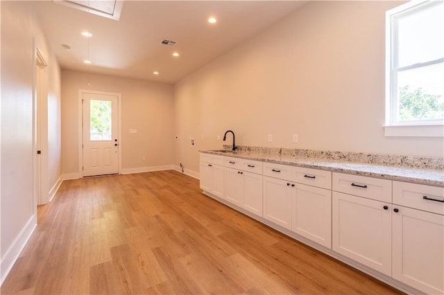 5144 Richland Ave, Marrero, LA 70072 - kitchen featuring a sink, light wood finished floors, white cabinets, baseboards, and light stone countertops
