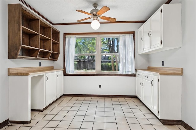 kitchen featuring white cabinets, light tile patterned floors, ceiling fan, crown molding, and wooden counters