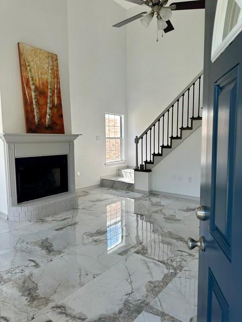 entrance foyer with ceiling fan, a high ceiling, and a fireplace