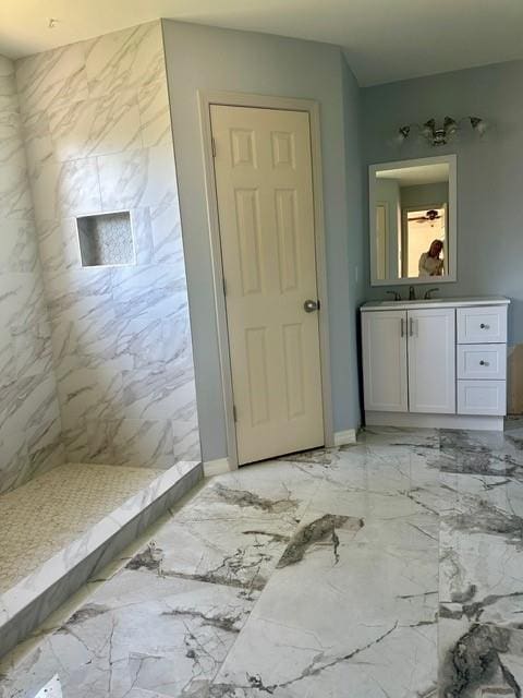 bathroom with a tile shower and vanity