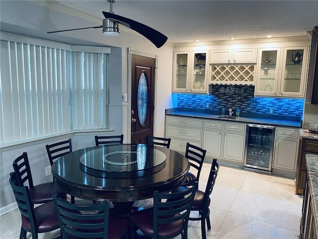 dining room with ceiling fan, a textured ceiling, bar area, and beverage cooler