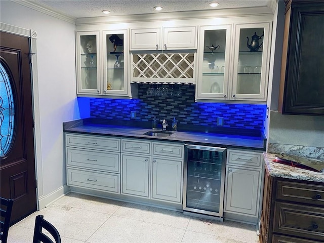 bar with gray cabinetry, tasteful backsplash, sink, a textured ceiling, and beverage cooler