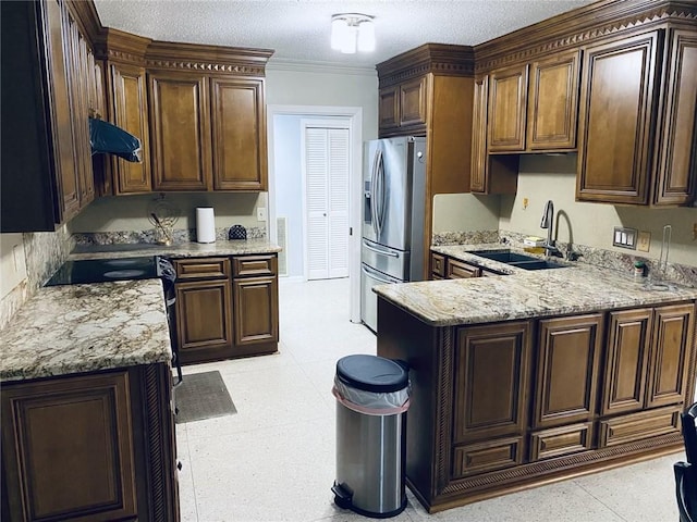 kitchen with light stone countertops, sink, stainless steel fridge with ice dispenser, and a textured ceiling