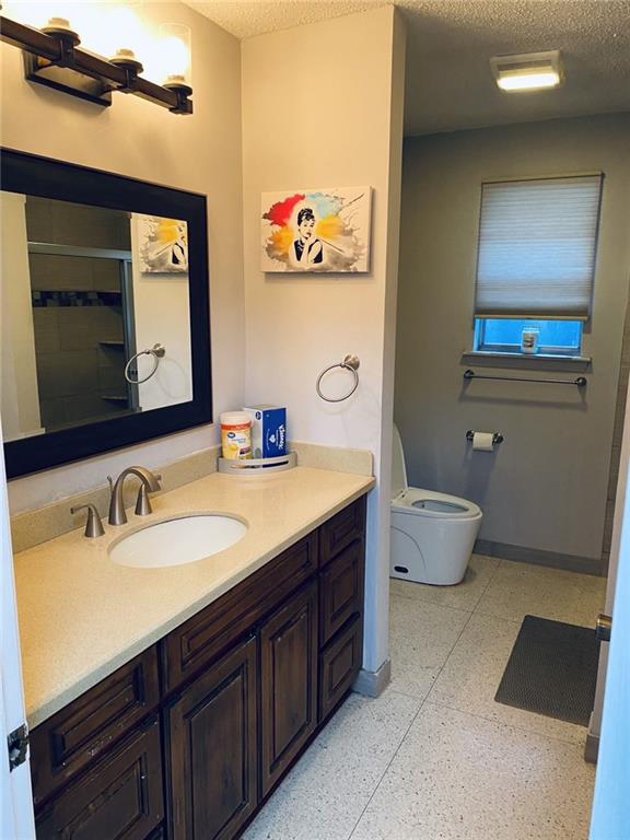 bathroom featuring toilet, an enclosed shower, a textured ceiling, and vanity