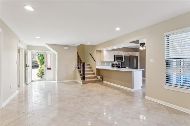 kitchen with a kitchen breakfast bar, kitchen peninsula, sink, white cabinets, and appliances with stainless steel finishes