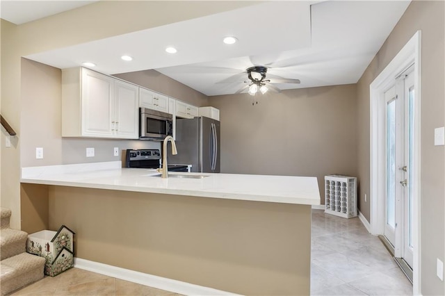 kitchen with appliances with stainless steel finishes, kitchen peninsula, white cabinetry, and sink