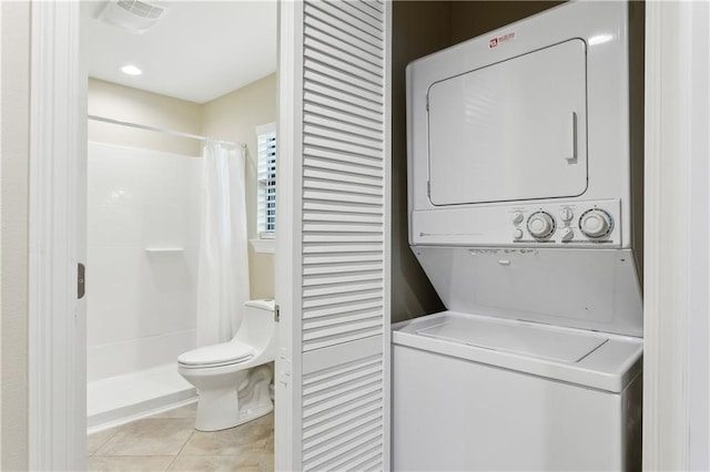 washroom with stacked washer / dryer and light tile patterned flooring