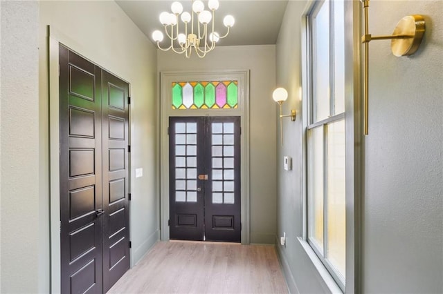 entryway with french doors, baseboards, an inviting chandelier, and wood finished floors