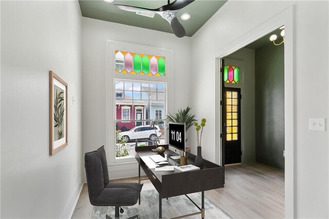 office area with light wood-type flooring, baseboards, a ceiling fan, and a wealth of natural light